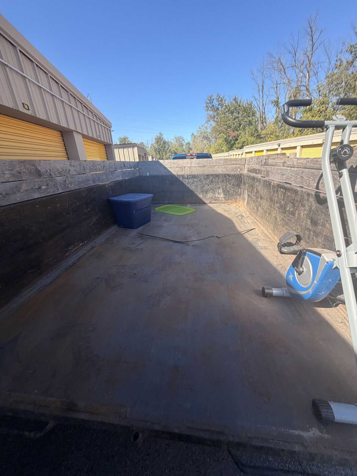 Inside of a Mathis Junk Removal 10 yard dump trailer loaded with a storage tote and an exercise bike during a storage unit cleanout